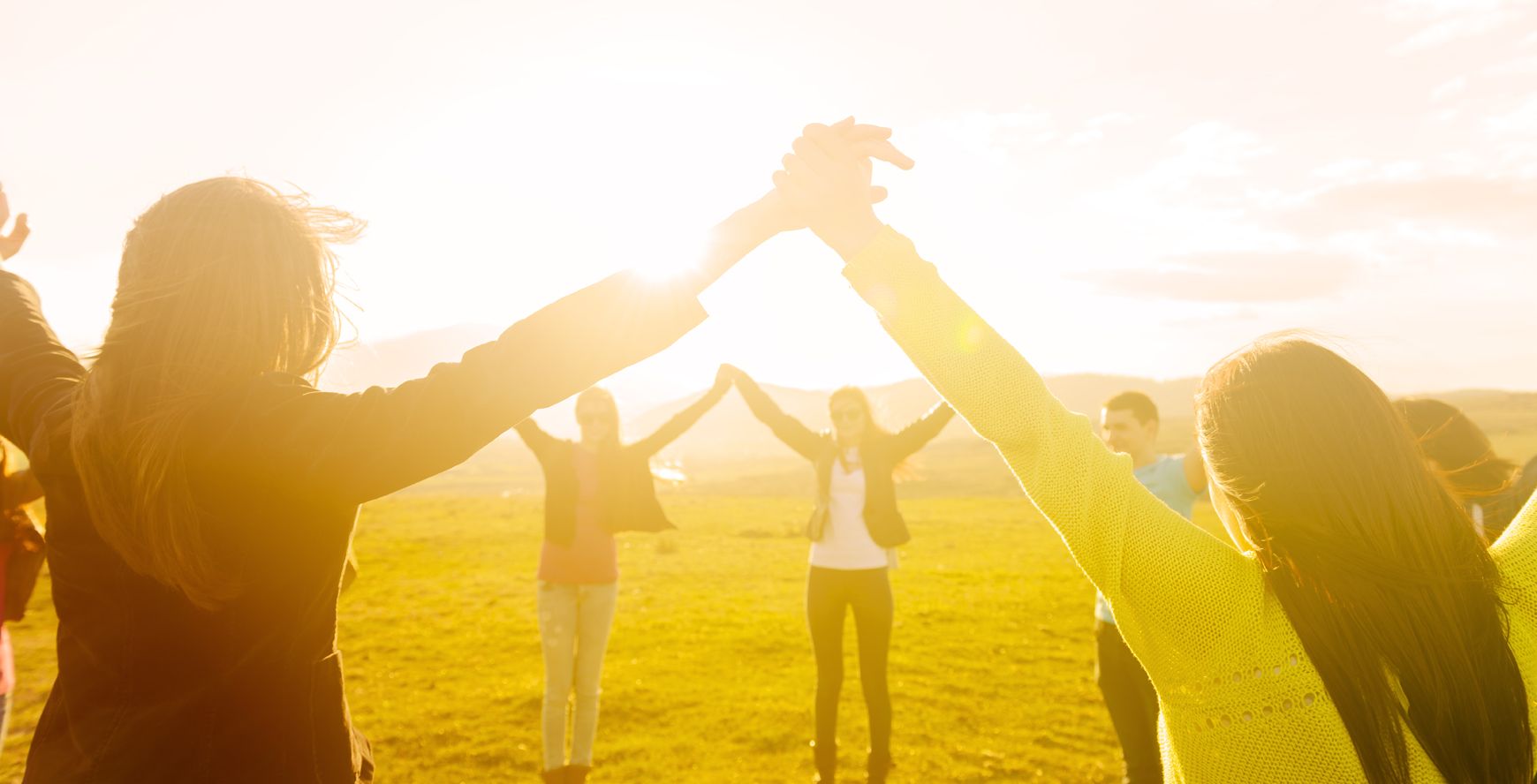 Group of people holding hands in the sunlight