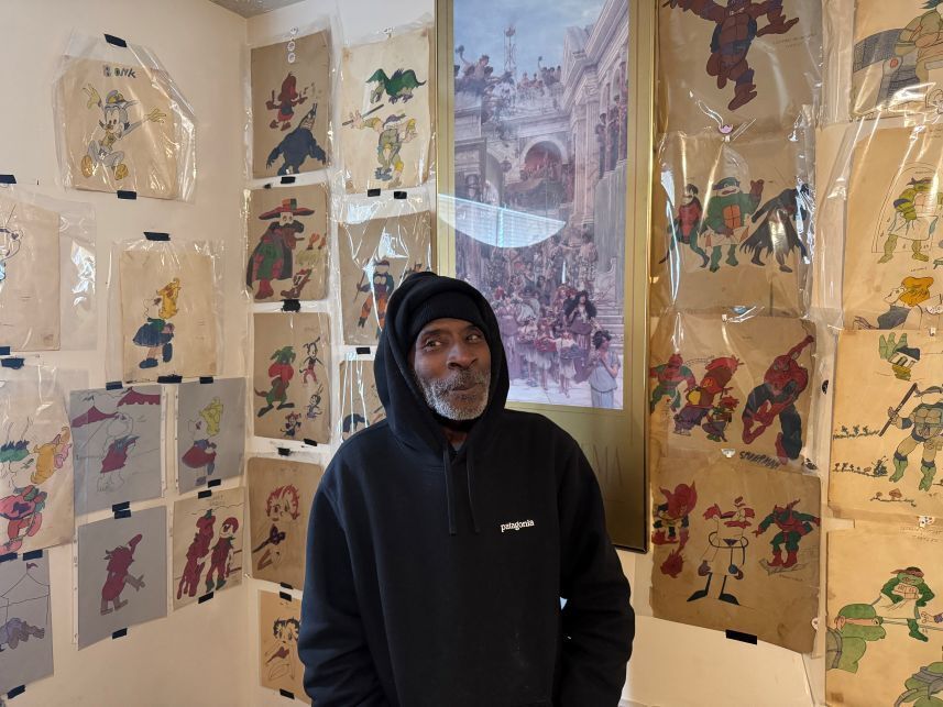 Man smiling in front of wall covered in cartoon drawings