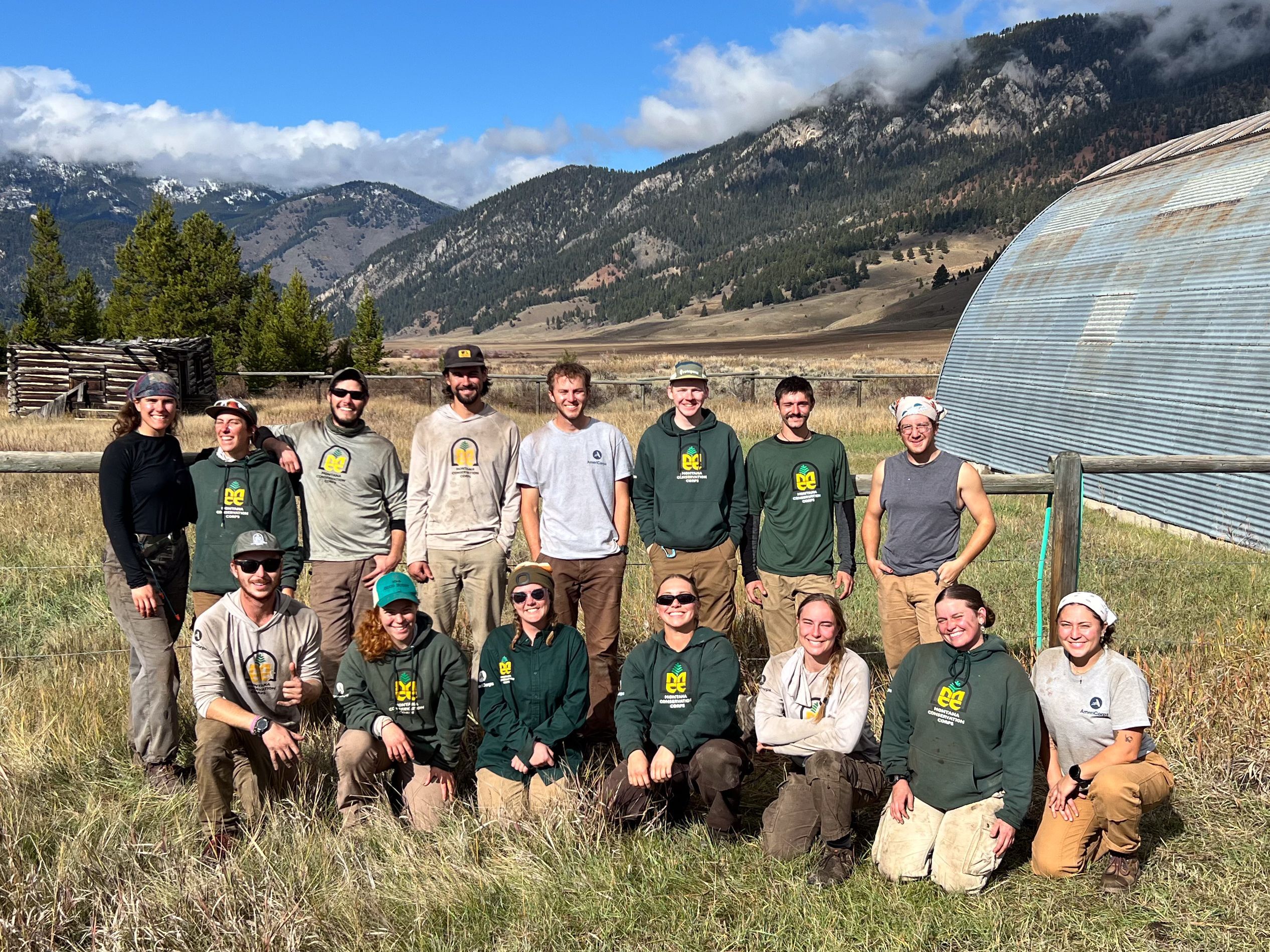 Three crews standing next to a metal shelter