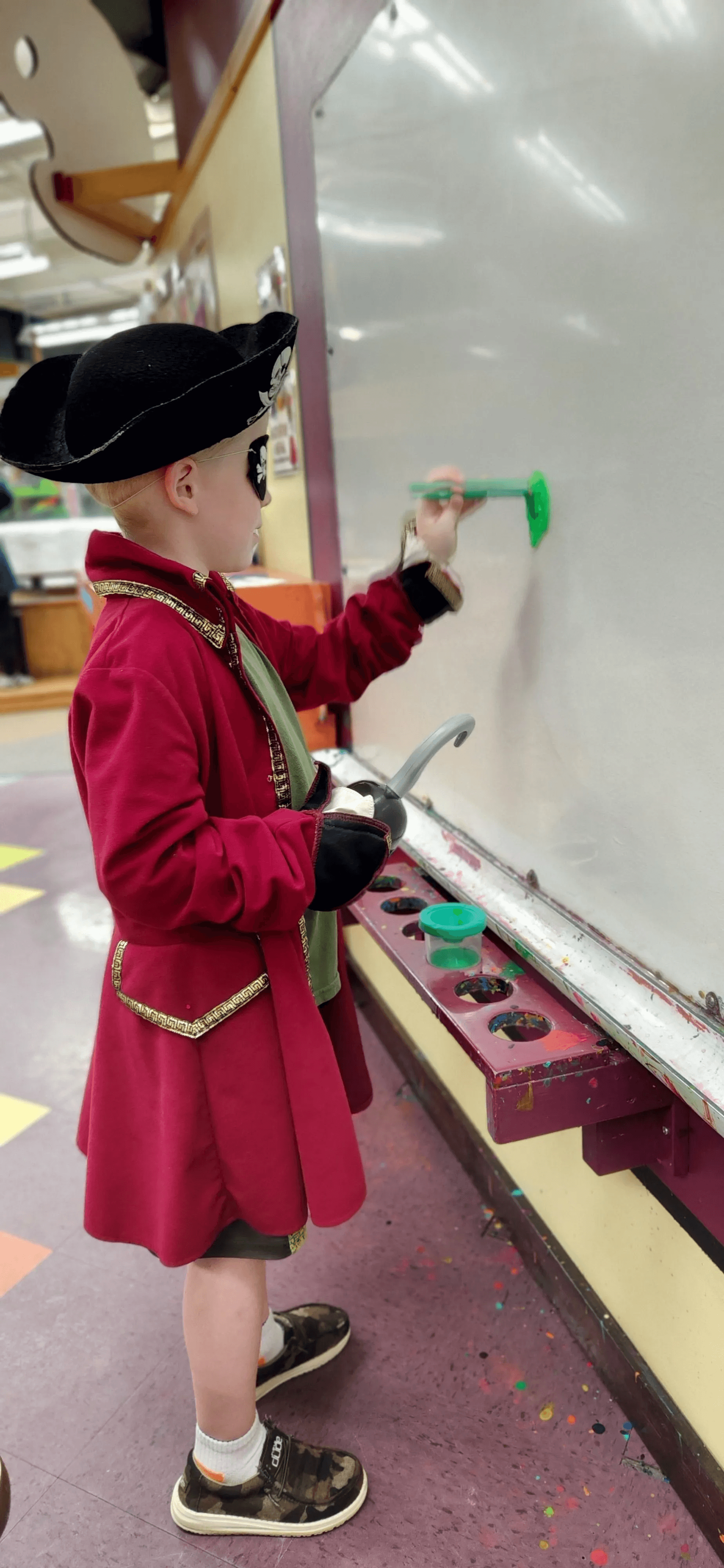 A kid dressed as a pirate, painting on the paint wall.