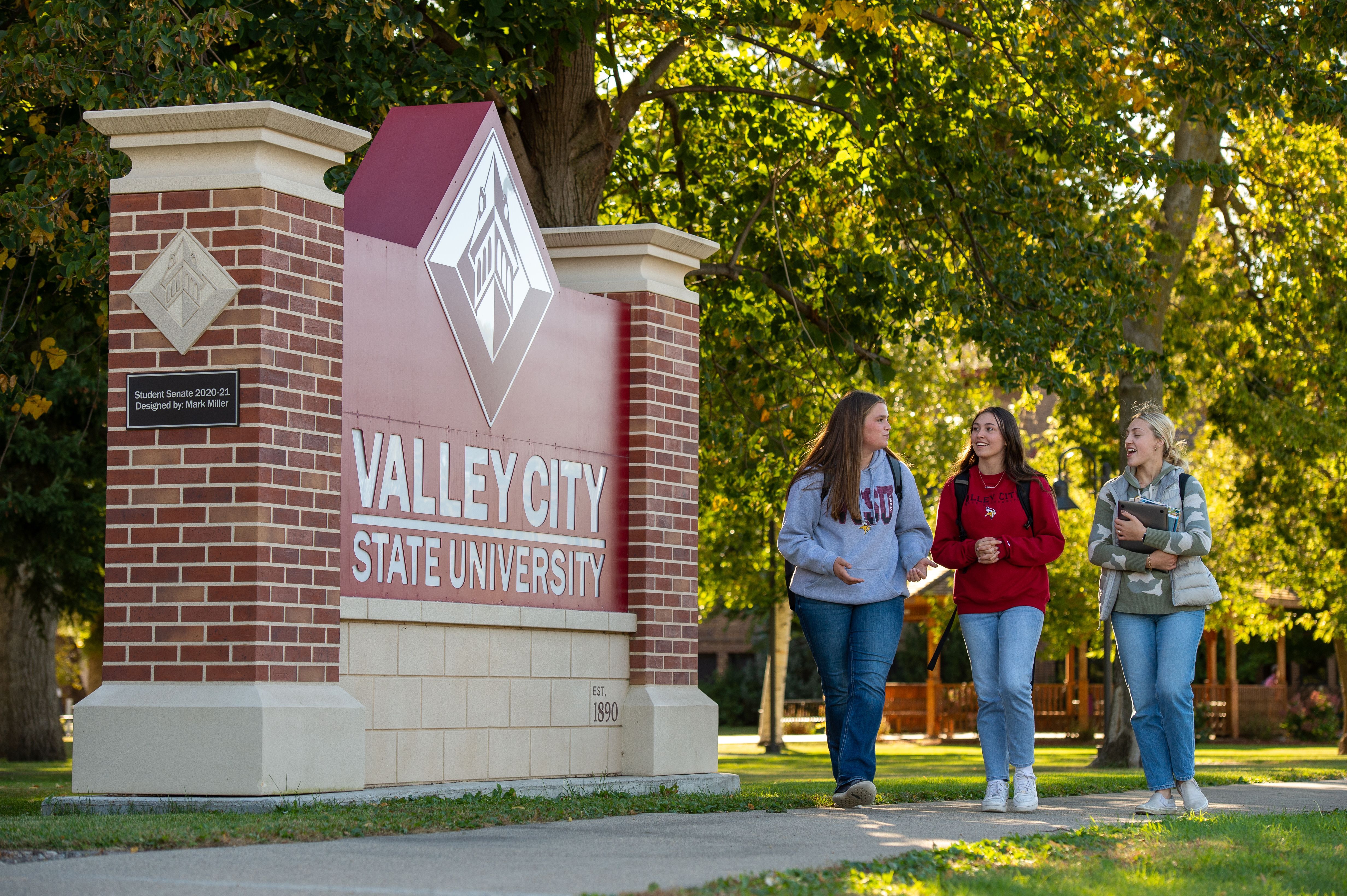 students walking in front of the Larry Robinson Center for the Arts, engaging in conversation and carrying backpacks