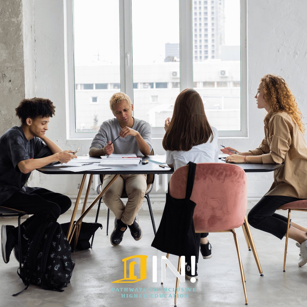 four students talking around a table with in logo