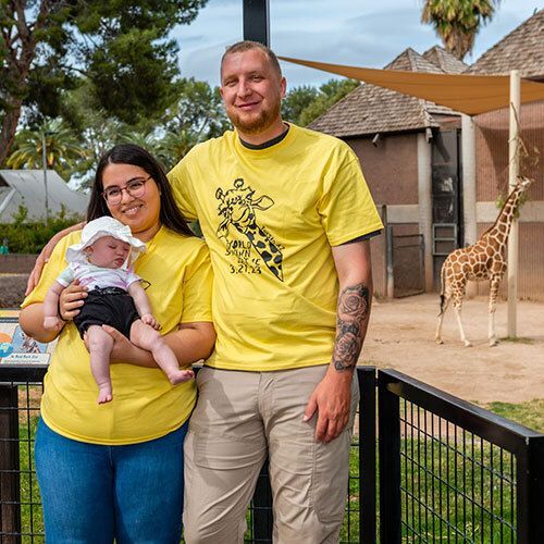 Family of three visiting giraffes at the zoo.