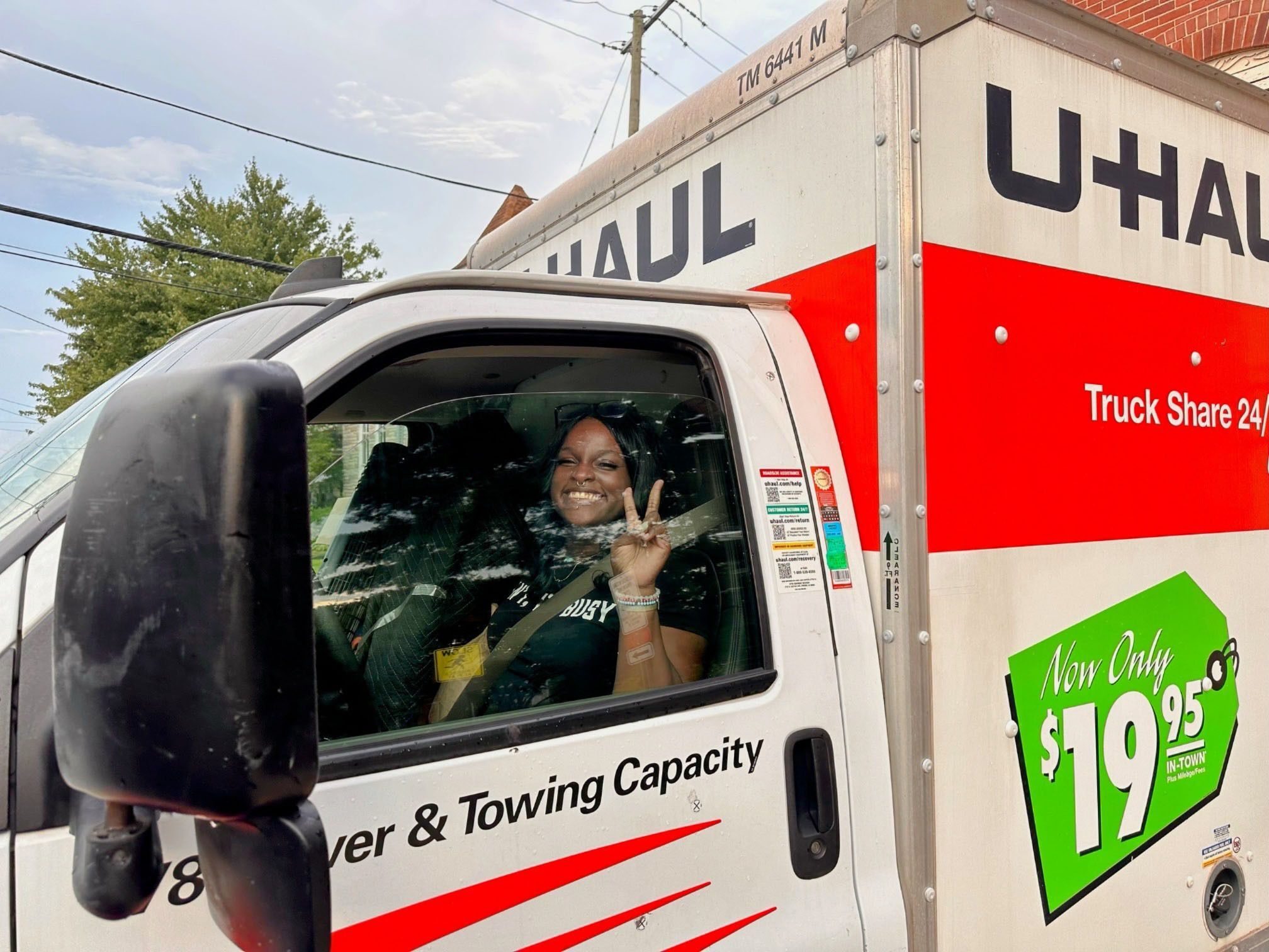 Woman smiling and waving from the driver's seat of a U-Haul truck