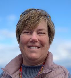 Board Member Trish Stoltzfus smiles at the camera, wearing a pink vest