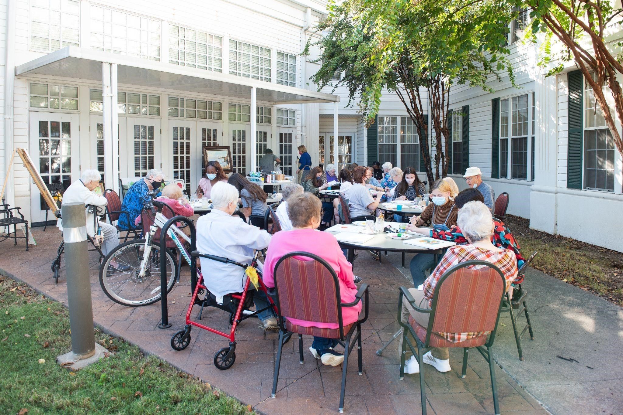  A group of college students and residents of the College Square Retirement Community gather at tables filled with art supplies.