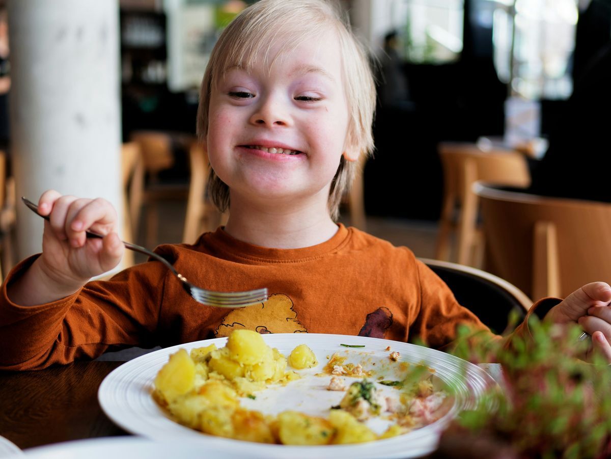 Young girl smiling in front of a plate of food