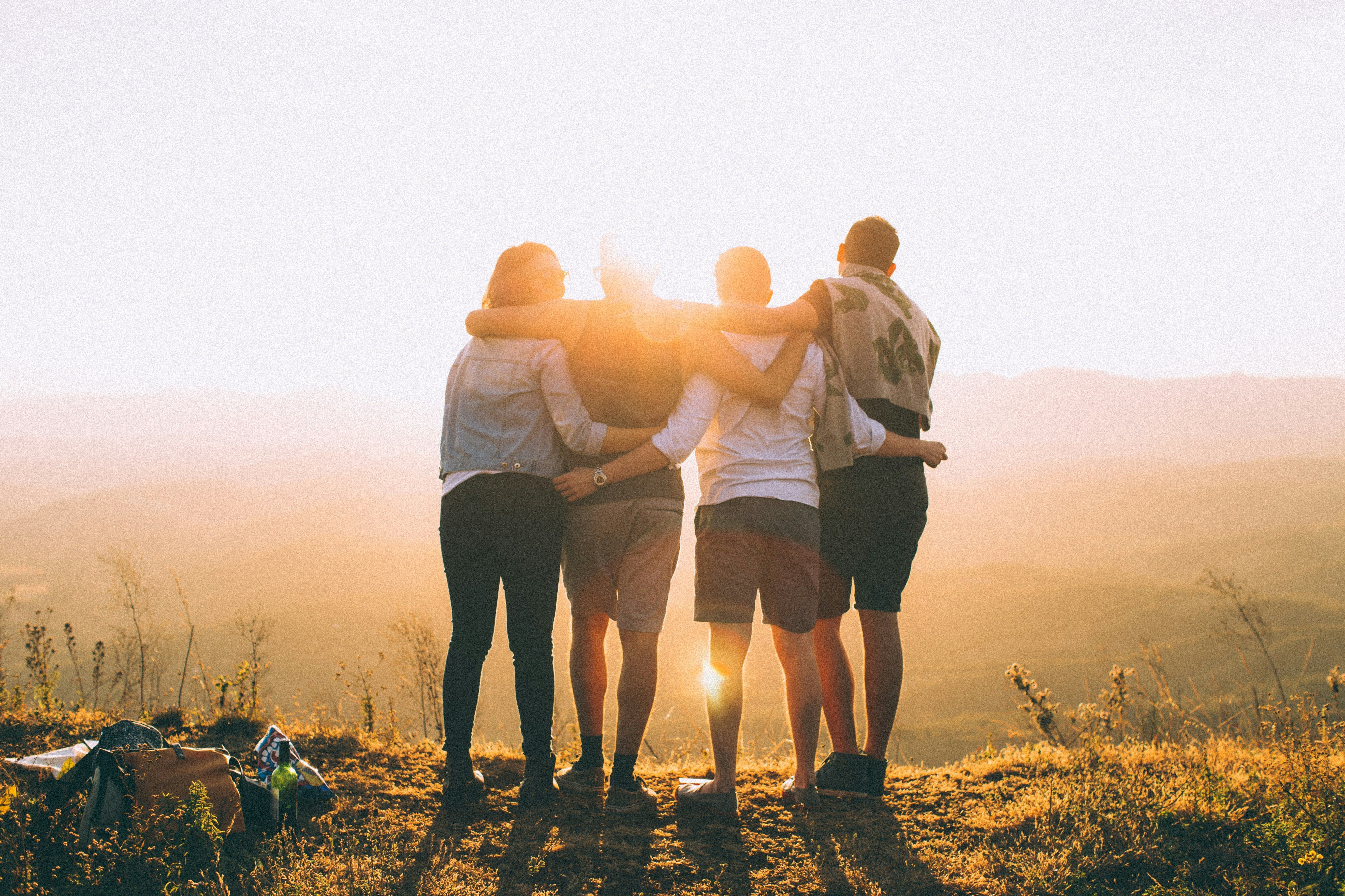 Photo of adults linking arms together during sunset.