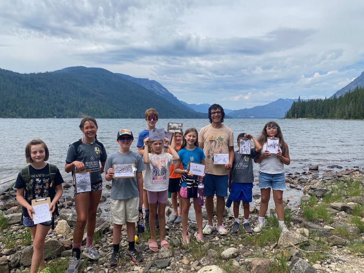 A group of campers pose with the charcoal painting artwork at Lake Wenatchee.