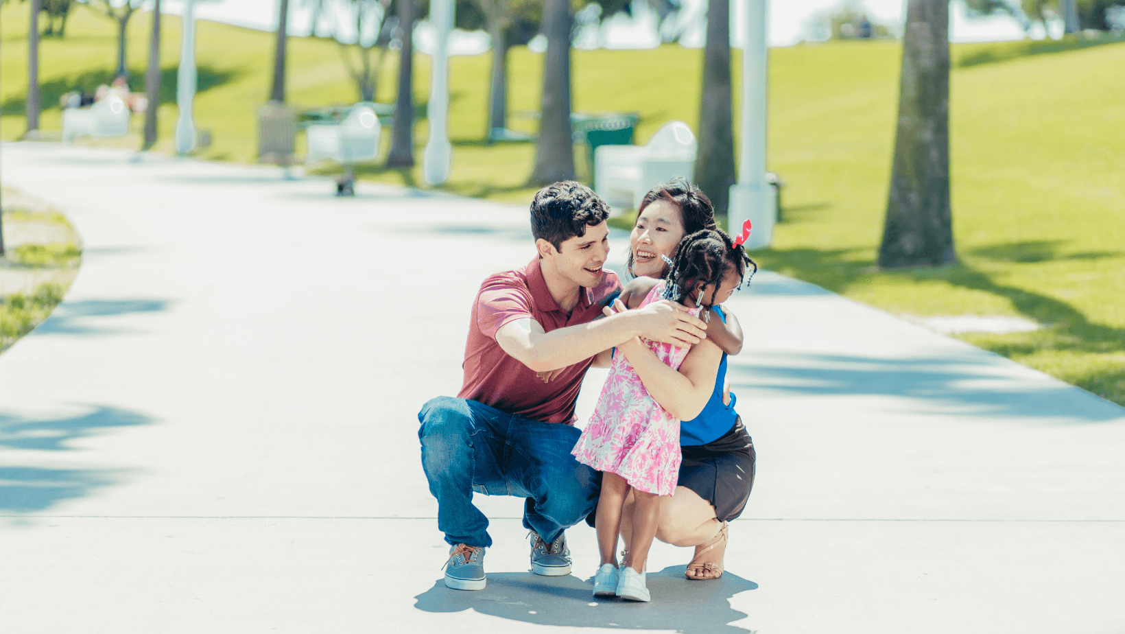 Young man and woman hugging a child on a sidewalk