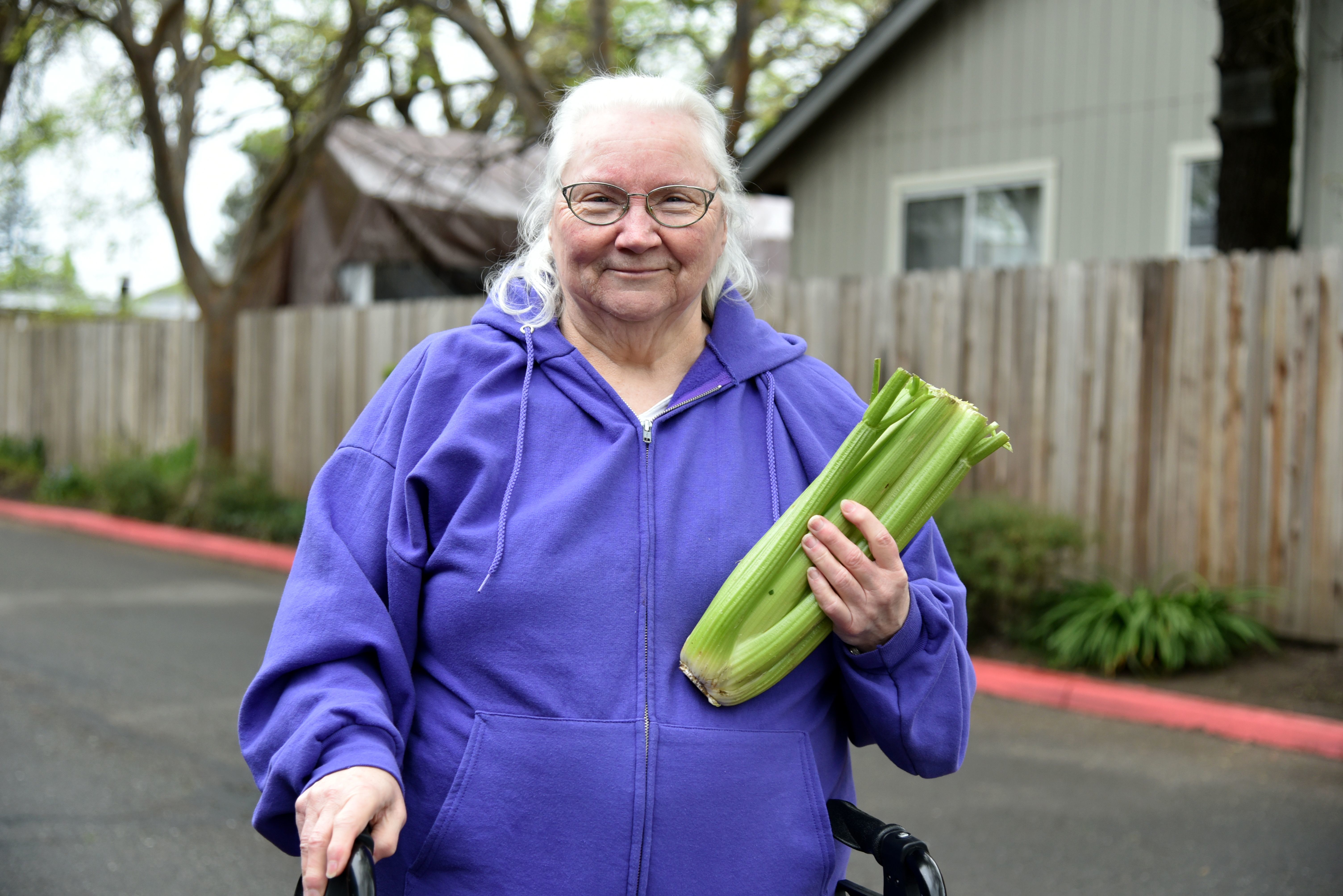 Senior woman with a walker holding fresh celery and smiling
