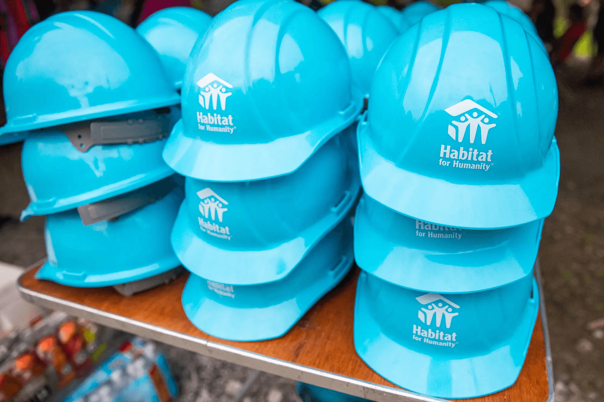 Stacked blue Habitat for Humanity hard hats on a table, ready for volunteers at a construction site or community build day