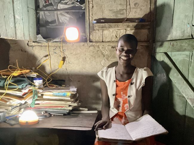 Tumaini student studying at home by solar-powered lights in Mwanza, Tanzania.