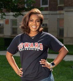 African American young lady with both hands on hips smiling and Howard University t-shirt on.
