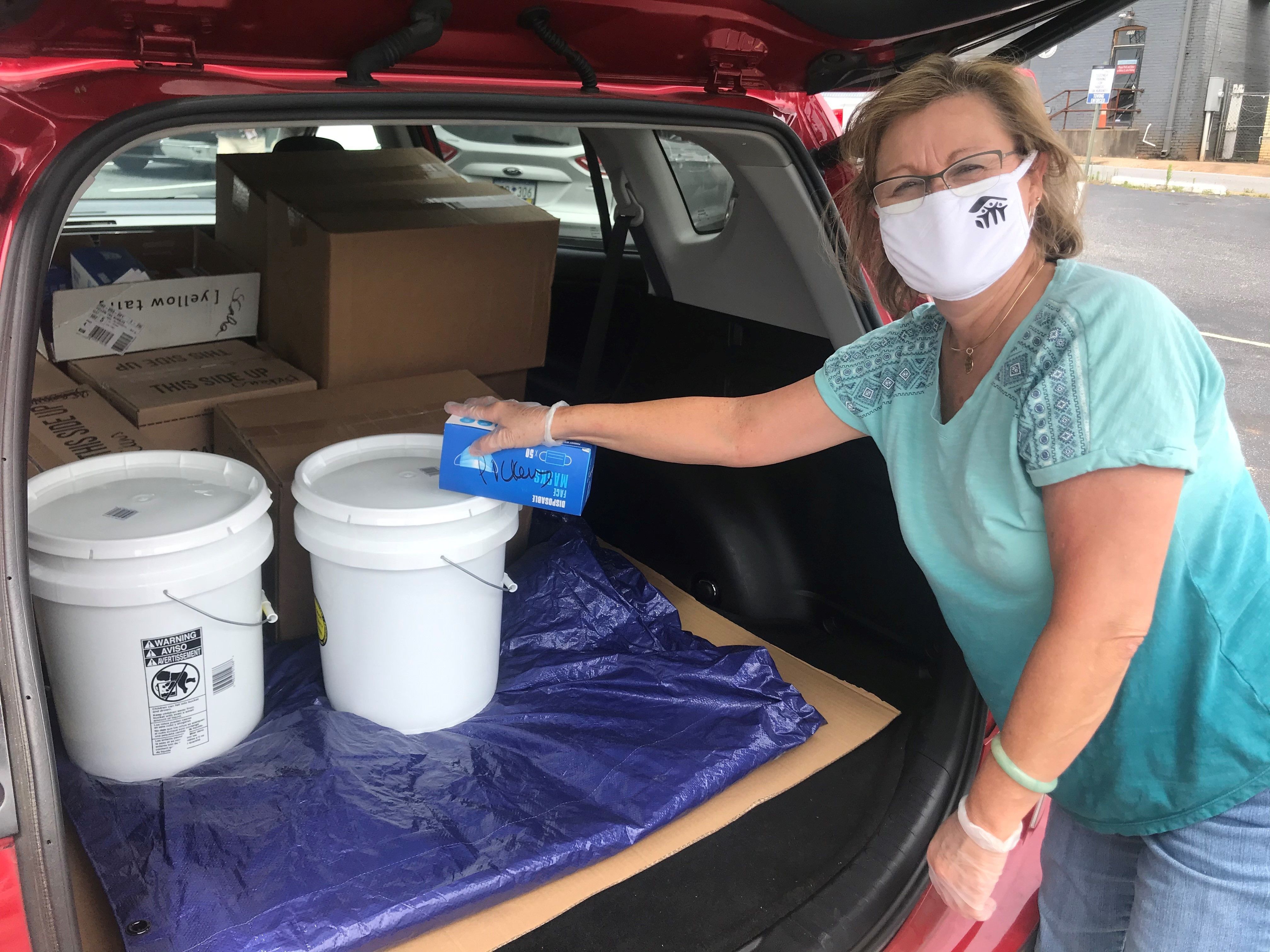 Executive Director Jill Evans stands with donated hand sanitizer and masks in the back of her vehicle. 