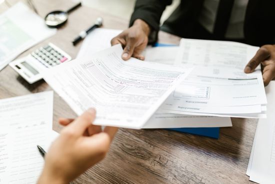 Two people reviewing printed account statements and forms at a desk, examples of documents produced through transactional printing.