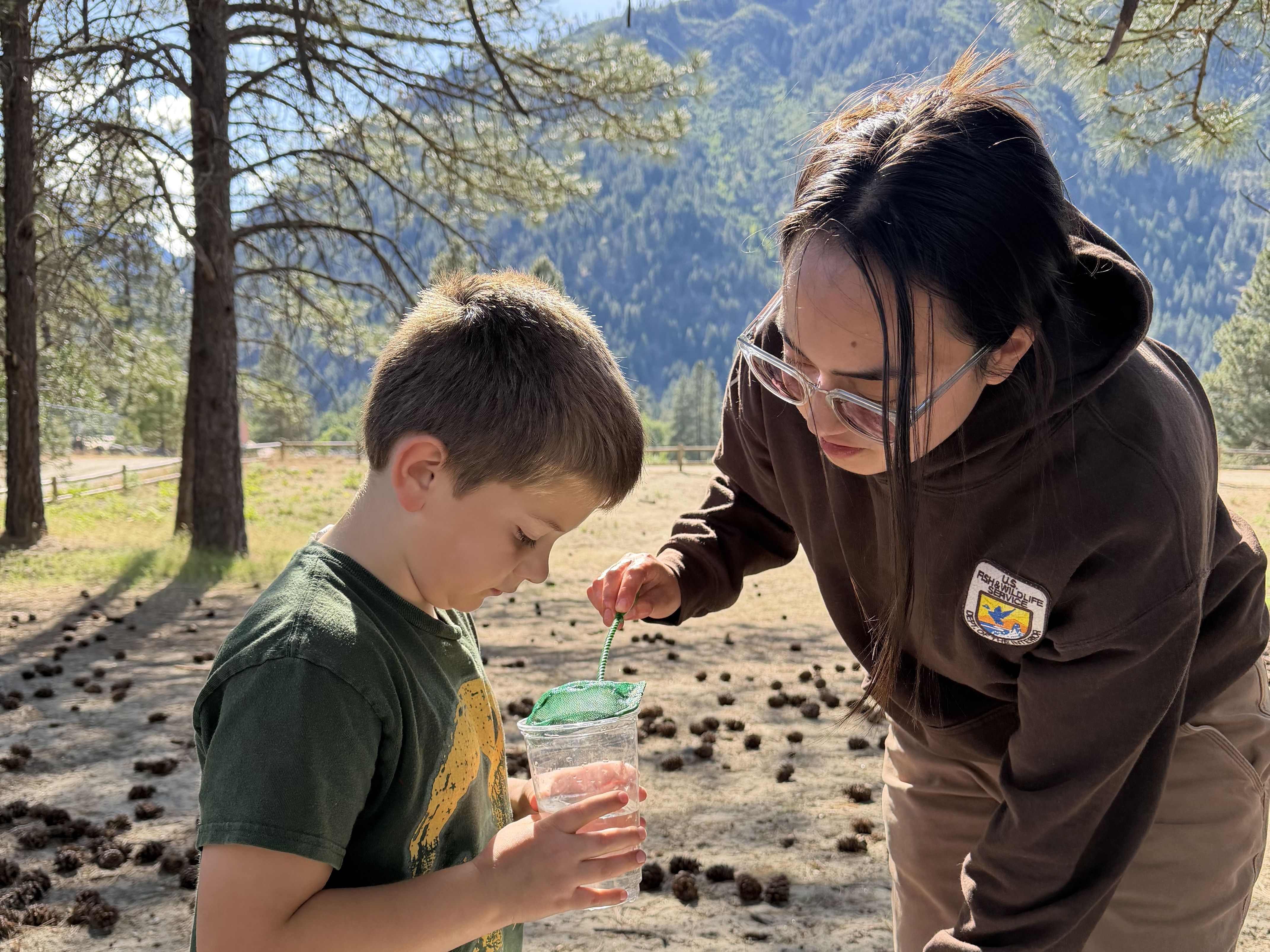 Sophia Troeh from partner, Leavenworth National Fish Hatchery, assisting a student during a fish release at the hatchery in spring 2026.
