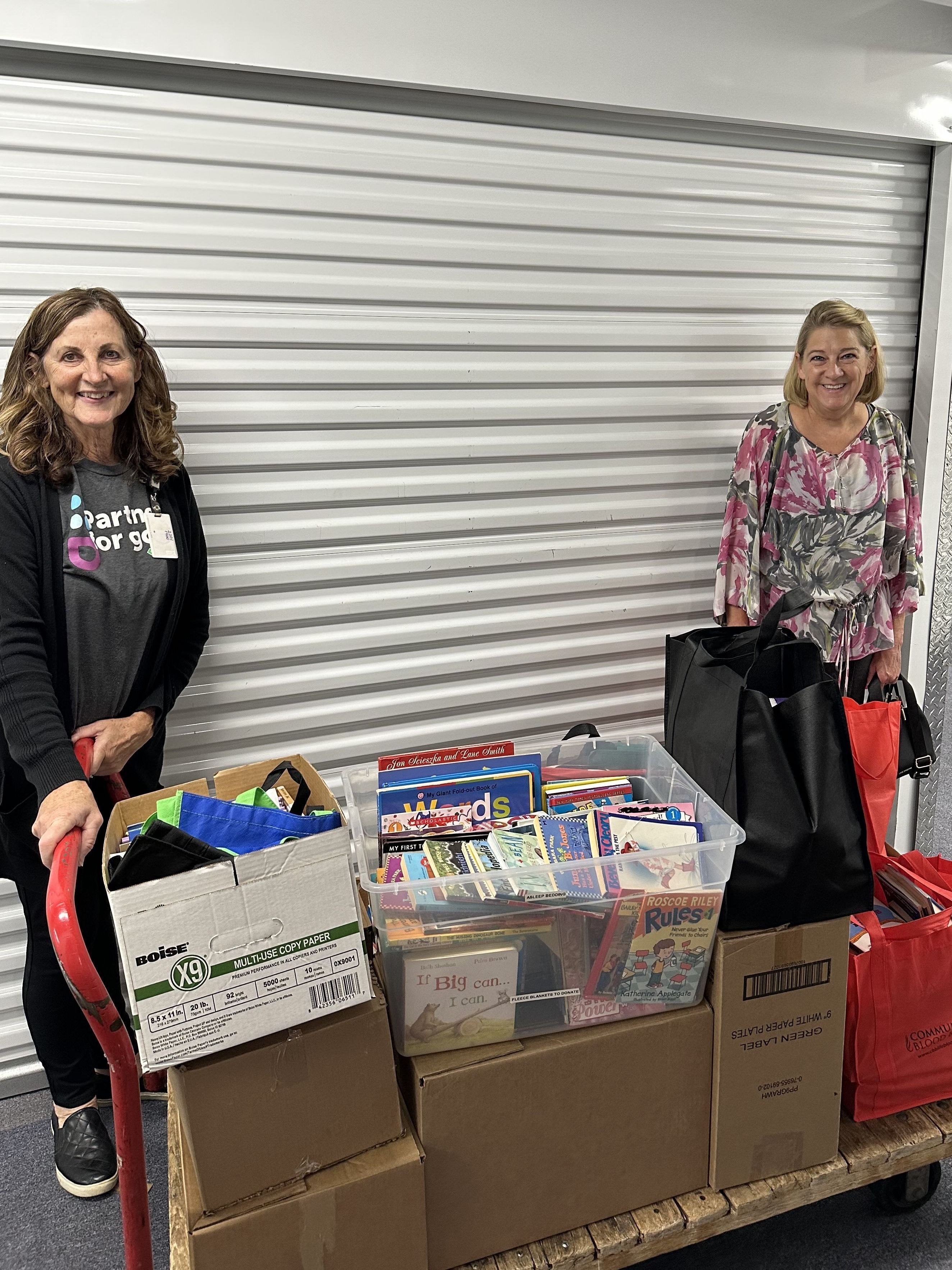 two women with cart loaded with boxes of children's books