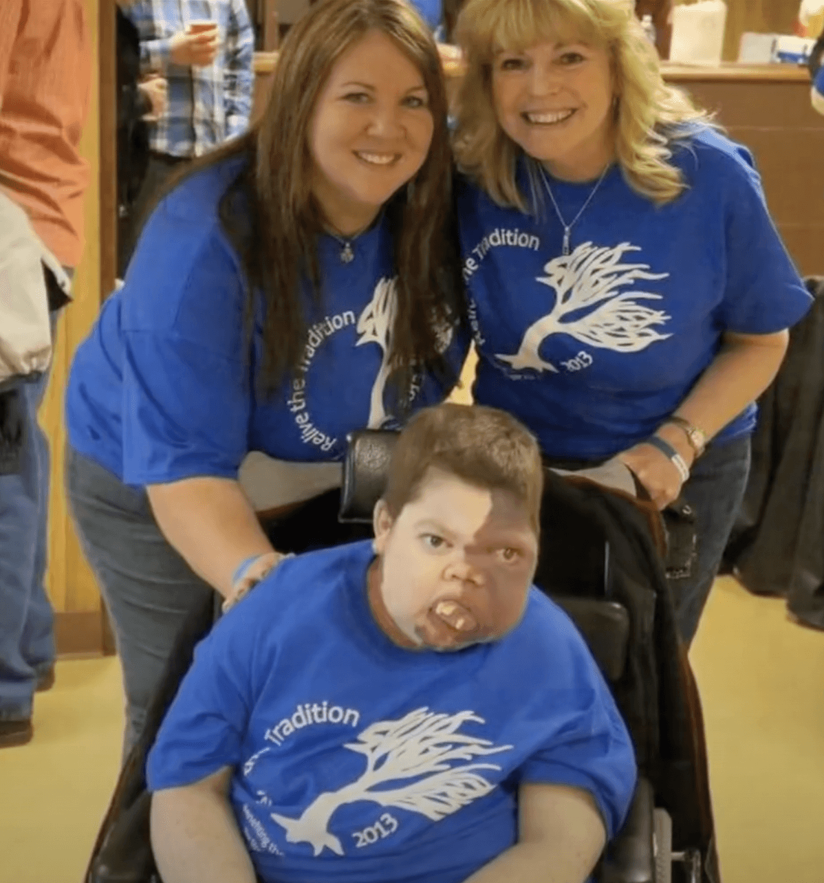 photo of two women standing behind Danny who is in a wheelchair