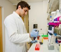 Young male researher in lab coat performing test