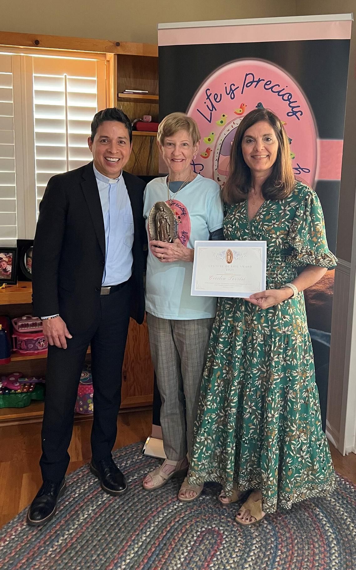 Cecilia Torrisi, center, accompanied by her pastor, Father Mario Castañeda, of St. Rita in Wellington, is presented with the 2025 Respect Life Ministry Award by Deanna Herbst-Hoosac, Respect Life director for Catholic Charities of the Diocese of Palm Beac