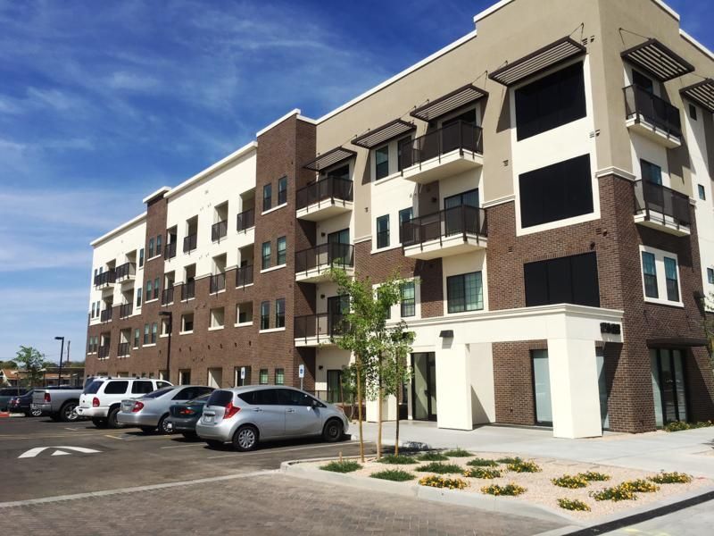 Four story apartment building. Cars parked out front.