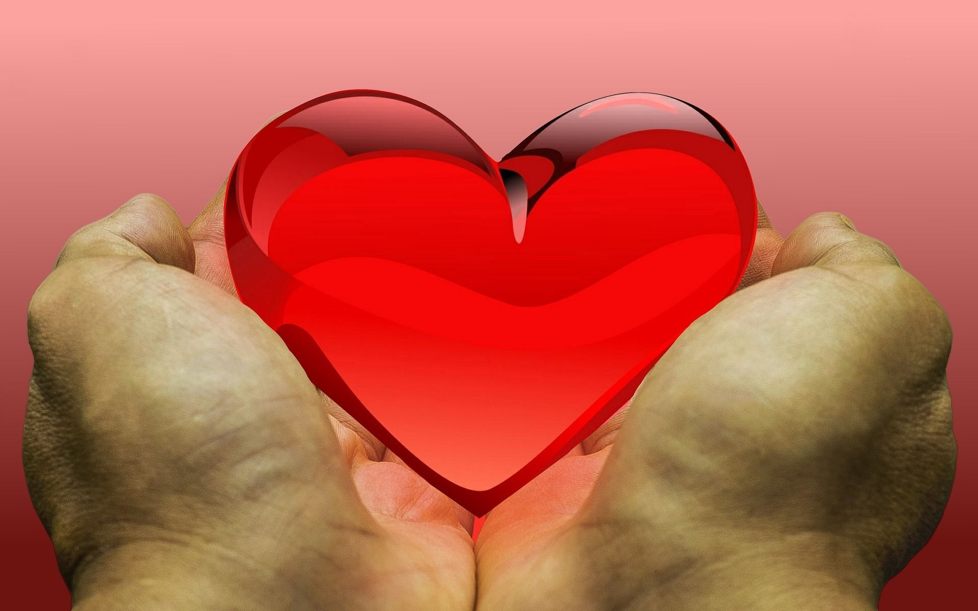 Two hand holding out a translucent red heart cupped in palms.
