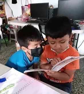 Two young boys reading a book.