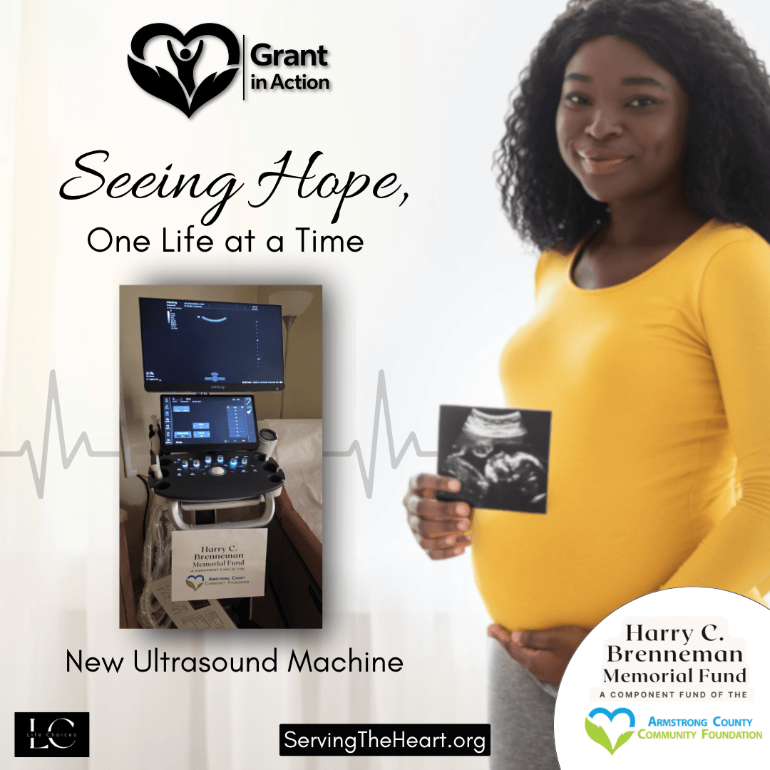 A pregnant women holding an ultrasound image alongside a newly installed machine at a local pregnancy support center.