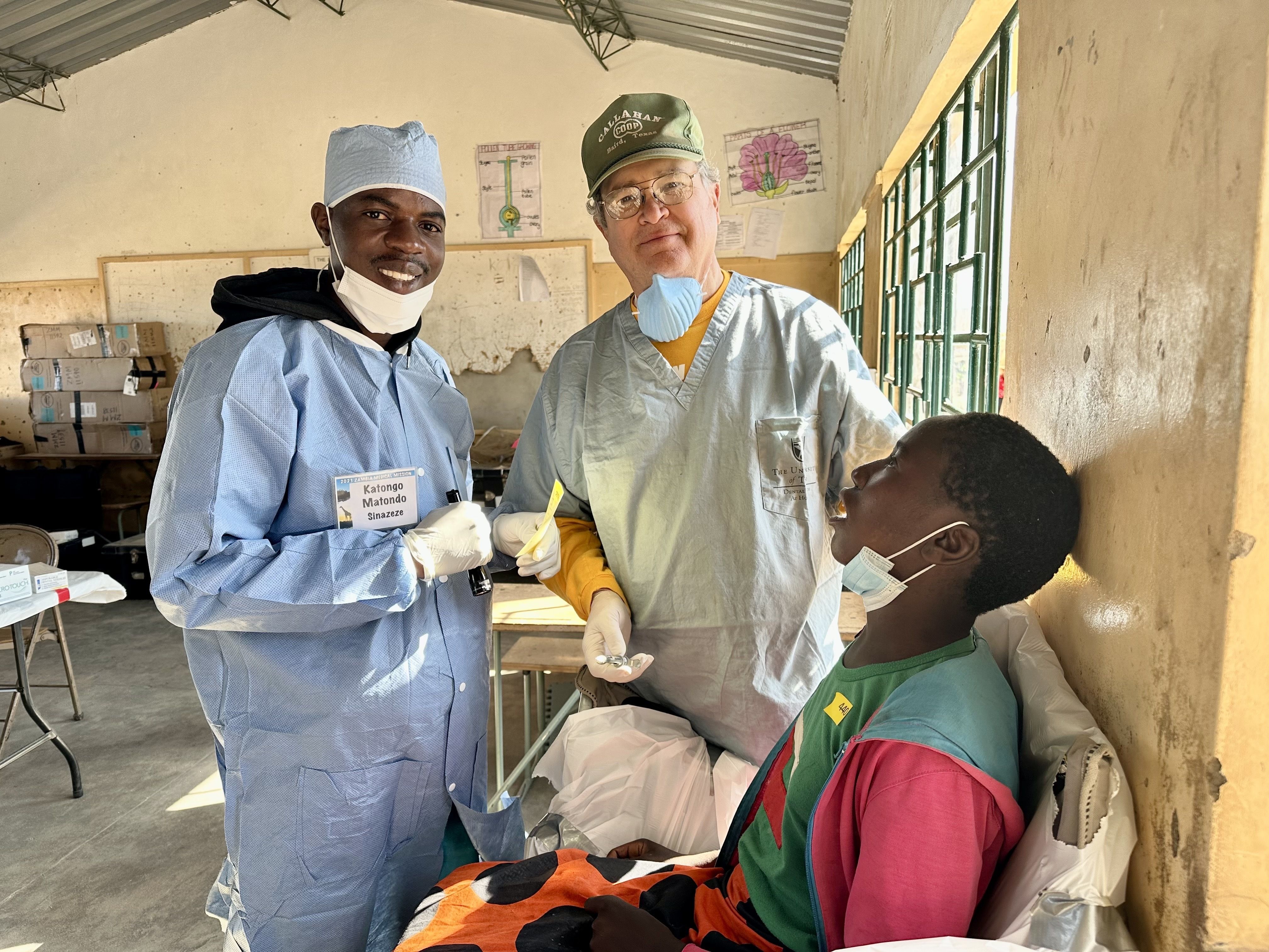 A Zambian dentist and Dr. John Estes III with a Zambian dental patient