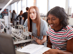 girls sitting at computer with model and blueprints