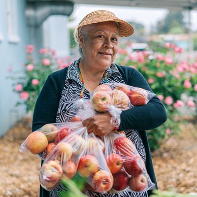Senior woman holding three bags of apples